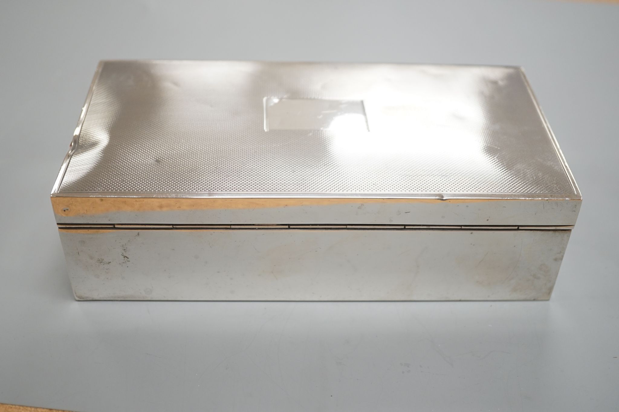 A late 1950's engine turned silver mounted rectangular cigarette box, with engraved inscription, 17.8cm.